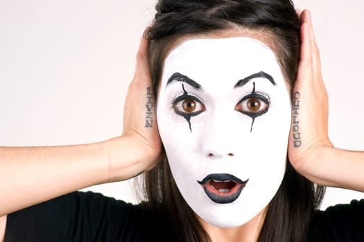 Woman made up in white face frames her features with her hands