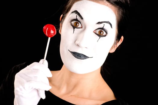 Woman made up in white face holds red sweet lollipop