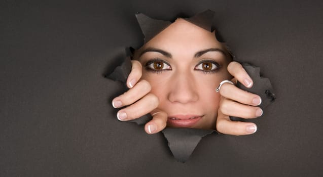 Bright Eyed Woman breaks through a hole and looks inside