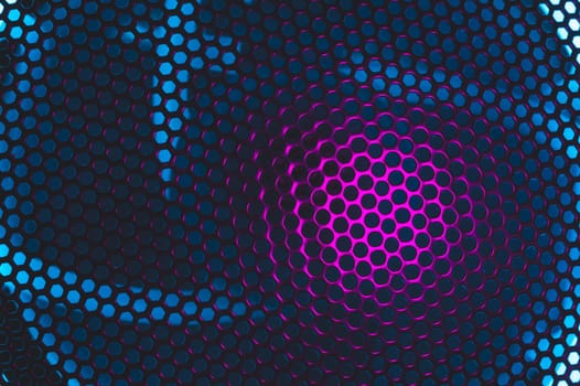 Colorful light of computer fan shines through the holes of protective grid. illumination glows in the dark. abstract futuristic background. led lighting of gaming pc