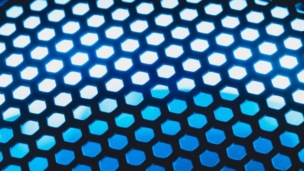 Blue light shines through the ventilation grid holes of computer air cooling system. abstract background