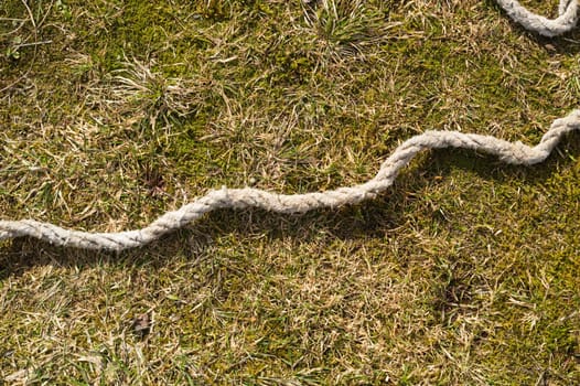 Old rope lies on the green grass. marine equipment