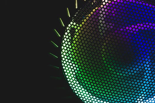 Colorful led lights of computer fan shines through the protective grid. illumination glows in the dark. abstract futuristic background