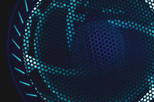 Colorful light of computer fan shines through the holes of protective grid. illumination glows in the dark. abstract futuristic background. led lighting of gaming pc