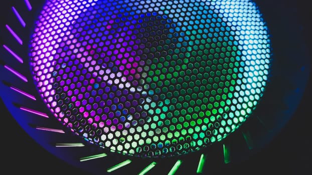 Colorful led lights of computer fan shines through the protective grid. illumination glows in the dark. abstract futuristic background