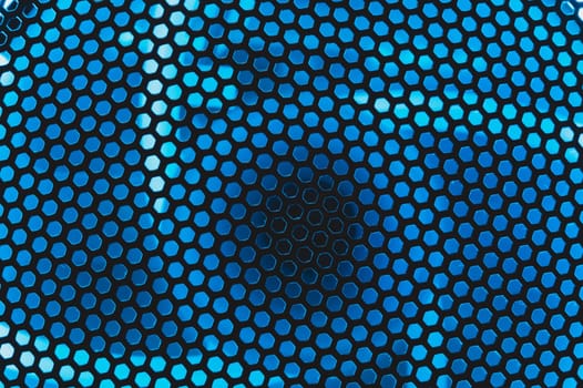 Blue light shines through the ventilation grid holes of computer air cooling system. abstract background