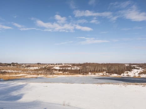Frozen river landscape with forest on a sunny day
