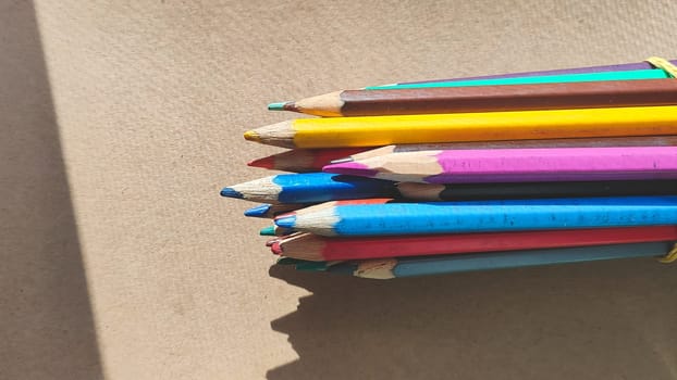Bunch of colorful pencils on cardboard close up