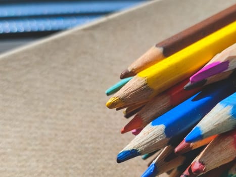 Bunch of colorful pencils on cardboard close up