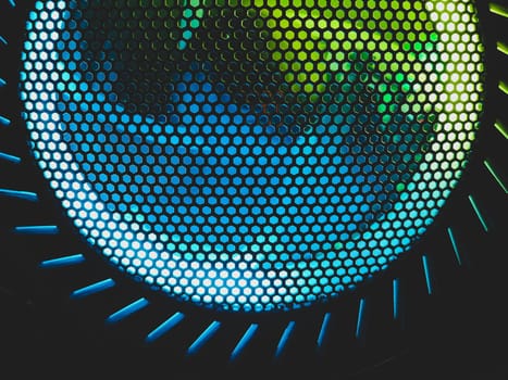 Colorful led lights of computer fan shines through the protective grid. illumination glows in the dark. abstract futuristic background