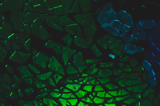 Shattered glass pattern in the dark. abstract cracked background. green and blue fragments