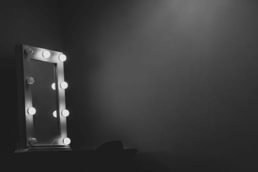 Makeup mirror with light bulbs in the dark room. Lamps around the frame