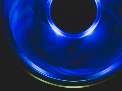 Computer cooling fan with blue light abstract background. cooler in action with led close up. power in motion concept