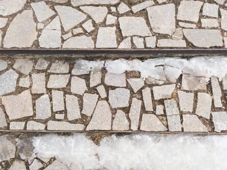 Melting snow on cobblestone pavement steps