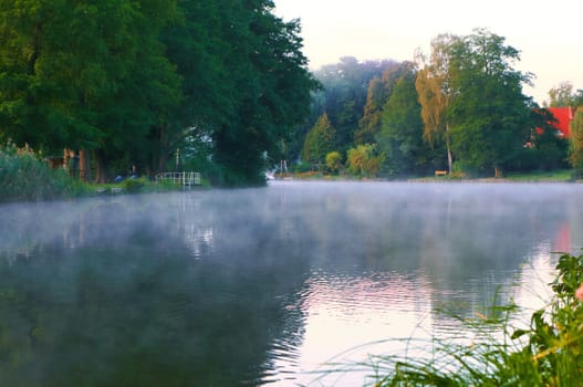 A sunrise at dawn, with fog on the river and warm light atmosphere. Landscape shot from nature in Brandenburg