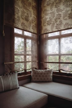 front view of divan with several pillows in front of window