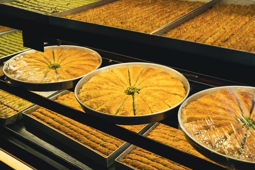 perspective view closeup of large plates of Arabic sweet baklava or baklawa on the shelves of street store window