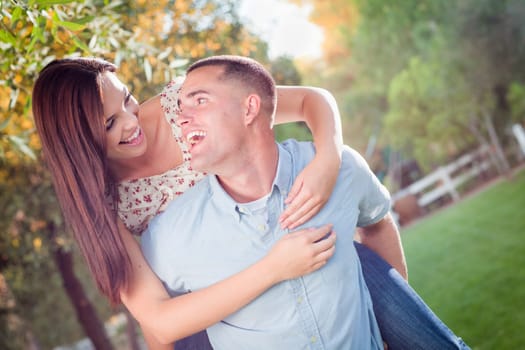Happy Romantic Caucasian Couple Piggyback Riding in the Park.