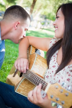 Young Adult Girl Playing Guitar with Boyfriend In The Park.