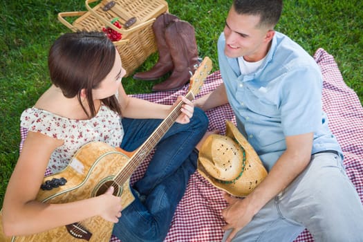 Young Adult Girl Playing Guitar with Boyfriend In The Park.