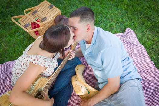 Young Adult Couple with Guitar Kissing in the Park.