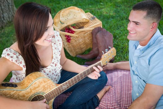 Young Adult Girl Playing Guitar with Boyfriend In The Park.