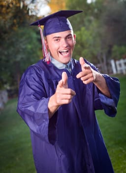 Happy Handsome Male Graduate in Cap and Gown Outside.