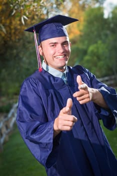 Happy Handsome Male Graduate in Cap and Gown Outside.