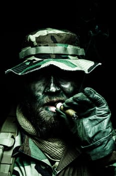 Brutal and serious commando soldier, army special forces veteran, in camouflage battle uniform, boonie hat, black paint on bearded face, combat knife in shoulder holder, smoking cigar, studio portrait toned and colorized