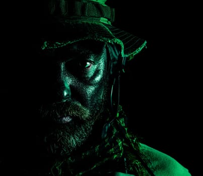 Special forces United States in Camouflage Uniforms studio shot. Wearing jungle hat, Shemagh scarf, painted face. Black background, bottom light colorized toned contour shor