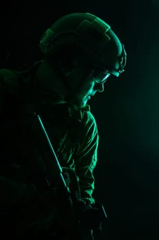 Studio contour backlight shot of special forces soldier in uniforms with weapons, portrait on black background