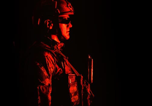 Half length low angle studio shot of special forces soldier in field uniforms with weapons, portrait on black background. Protective goggles glasses are on