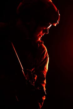 Studio contour backlight shot of special forces soldier in uniforms with weapons, portrait on black background