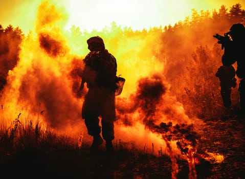 United States Marines in action. Military action, desert battlefield, smoke grenades., fire and explosions. Sun setting, dark silhouette in the desert