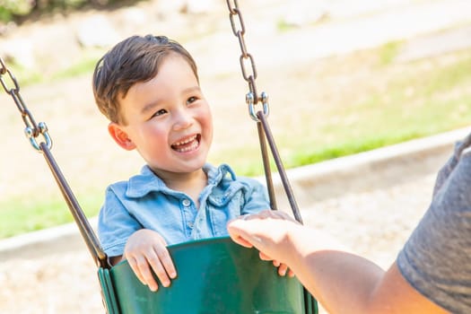 Chinese and Caucasian Boy Having Fun On The Swings At Playground.