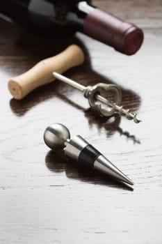 Abstract Wine Bottle, Corkscrew and Stopper Laying on a Reflective Wood Surface.