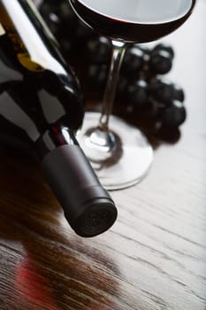 Abstract Wine Bottle, Glass and Grapes on a Reflective Wood Surface.