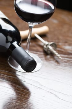 Abstract Wine Bottle, Glass and Corkscrew Laying on a Reflective Wood Surface.