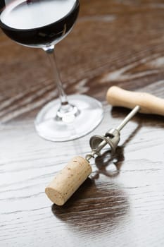 Abstract Wine Glass, Cork and Corkscrew Laying on a Reflective Wood Surface.