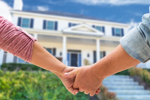 Couple Holding Hands Approaching Front Door Of New House.