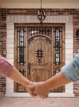 Couple Holding Hands Approaching Front Door of House.