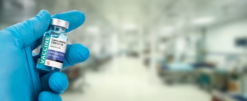 Doctor or Nurse Holding Coronavirus COVID-19 Vaccine Vial Within Hospital Banner.