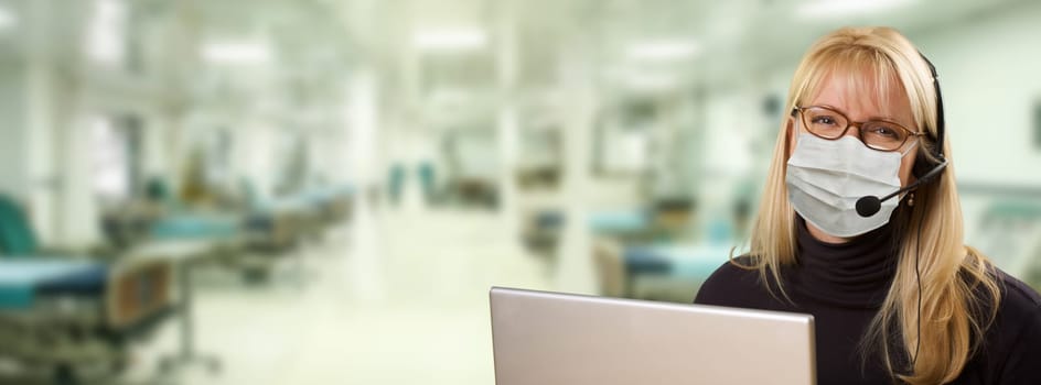 Woman Sitting at Computer with Phone Headset Within Hospital.