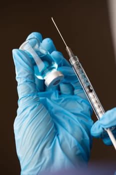 Doctor or Nurse Wearing Surgical Gloves Holding Vaccine Vial and Medical Syringe.
