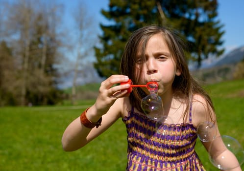 a little girl making soap bubbles in nature