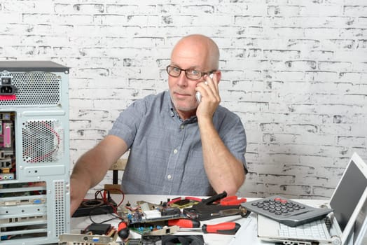a technician repairing a computer and phone to the customer