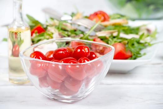Small tomatoes in a glass jar with seasonal salad