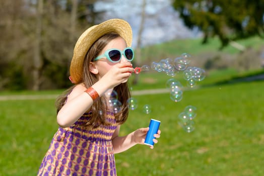 a little girl with sunglasses making soap bubbles