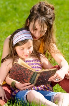 Mom and daughter reading a book in nature