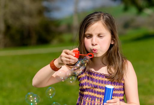 a little girl making soap bubbles in nature